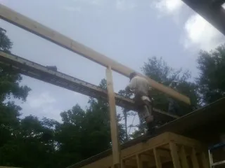 Carpenter setting a ridge beam over a new addition frame — Ice Dam Removal by Roofing Brothers in Round Mountain